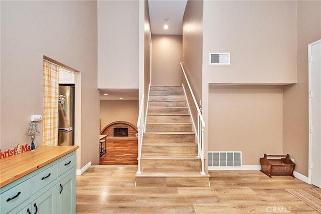 stairs featuring a towering ceiling, a fireplace, and hardwood / wood-style flooring