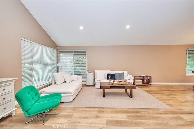 living room featuring lofted ceiling and light hardwood / wood-style floors