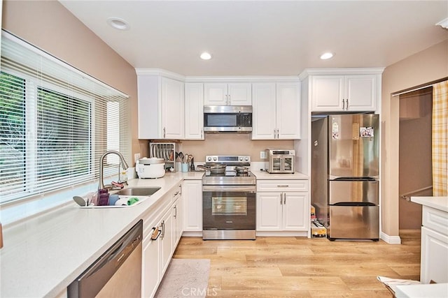 kitchen featuring white cabinetry, sink, stainless steel appliances, and light hardwood / wood-style floors