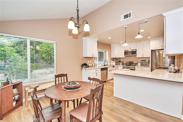 dining space featuring vaulted ceiling, sink, a chandelier, and light hardwood / wood-style flooring