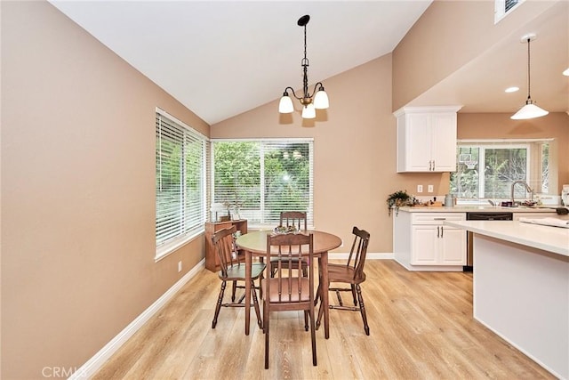 dining area featuring vaulted ceiling, sink, an inviting chandelier, and light hardwood / wood-style floors