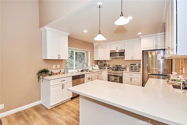 kitchen featuring decorative light fixtures, white cabinetry, sink, stainless steel appliances, and light wood-type flooring