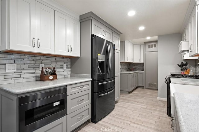 kitchen with light hardwood / wood-style floors, white range with gas stovetop, gray cabinets, refrigerator with ice dispenser, and built in microwave