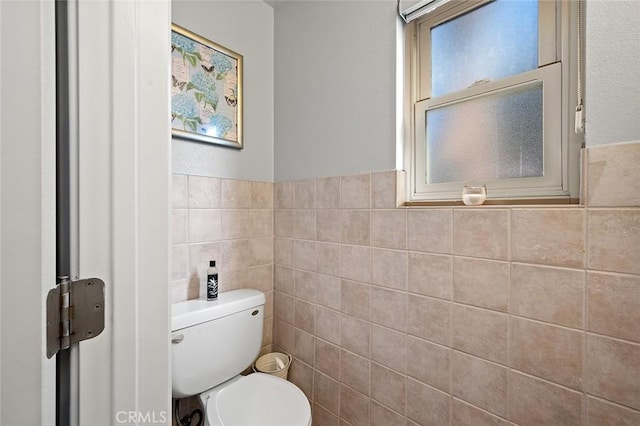 bathroom with toilet and tile walls