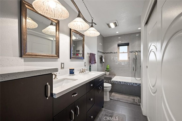 full bathroom with toilet, vanity, tile patterned flooring, and tiled shower / bath