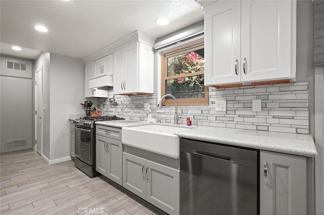 kitchen featuring double oven range, white cabinetry, dishwasher, and sink