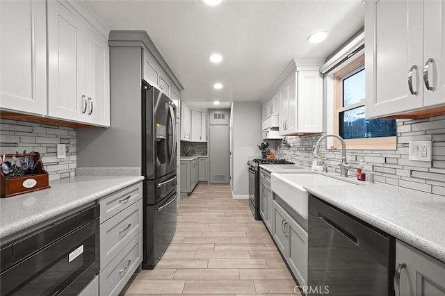 kitchen with appliances with stainless steel finishes, sink, white cabinetry, and light hardwood / wood-style floors