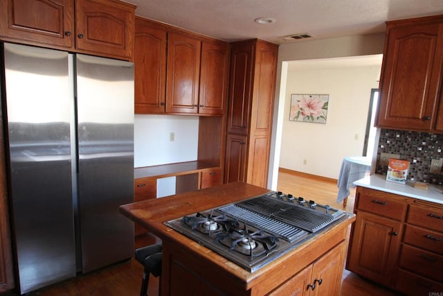 kitchen with a kitchen island, dark hardwood / wood-style flooring, stainless steel refrigerator, and gas stovetop