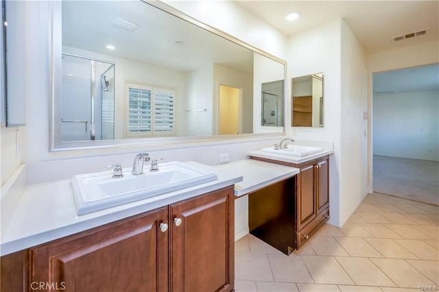 bathroom with a shower with shower door, tile patterned floors, and vanity