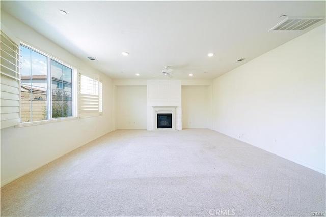 unfurnished living room with light carpet, ceiling fan, and a fireplace