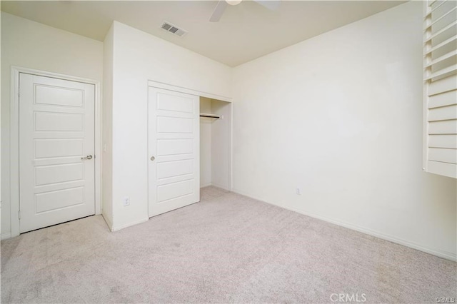 unfurnished bedroom featuring ceiling fan, a closet, and light carpet