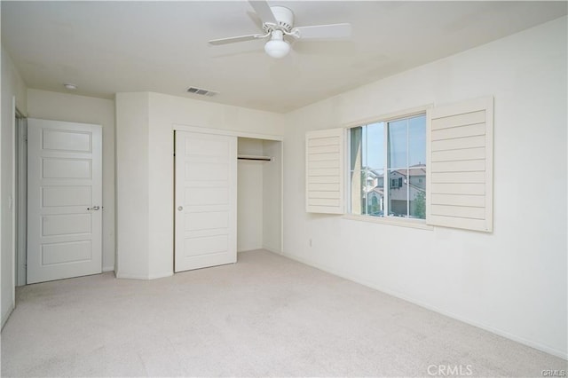 unfurnished bedroom featuring a closet, light colored carpet, and ceiling fan