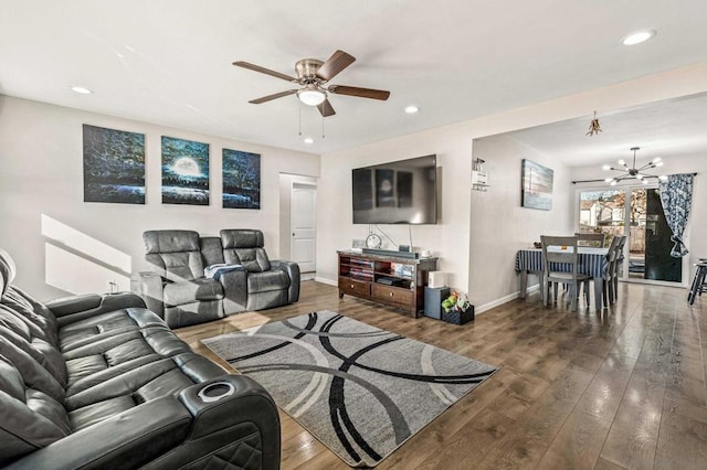 living room with dark hardwood / wood-style flooring and ceiling fan with notable chandelier