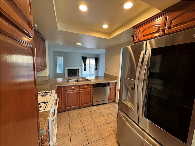 kitchen with a tray ceiling, light tile patterned floors, recessed lighting, appliances with stainless steel finishes, and a sink