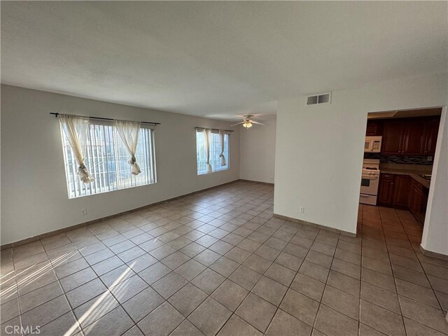 unfurnished room with light tile patterned floors, ceiling fan, and visible vents