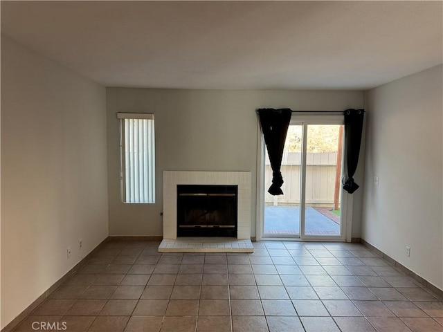 unfurnished living room featuring a fireplace, baseboards, and light tile patterned flooring