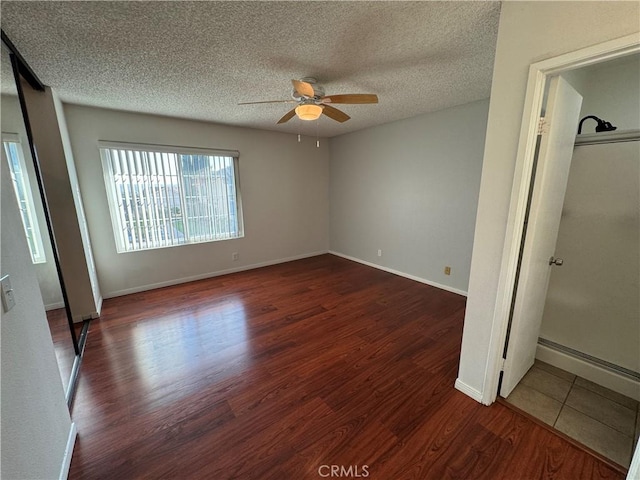 unfurnished bedroom featuring dark wood-style floors, ceiling fan, baseboards, and a textured ceiling