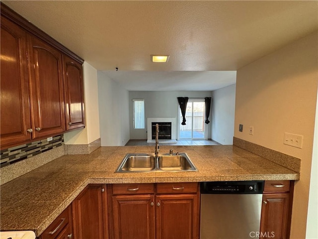 kitchen with tile countertops, stainless steel dishwasher, a fireplace with flush hearth, open floor plan, and a sink