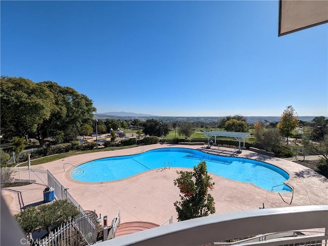 pool featuring a patio, fence, and a mountain view