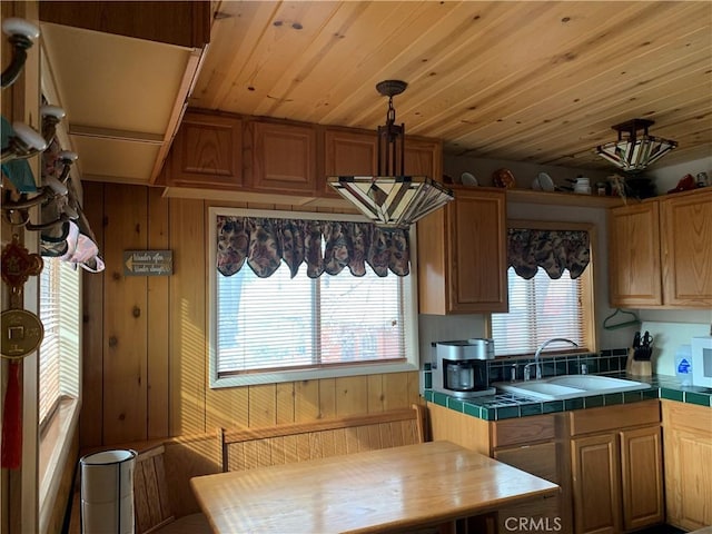 kitchen featuring tile counters, sink, and wooden walls