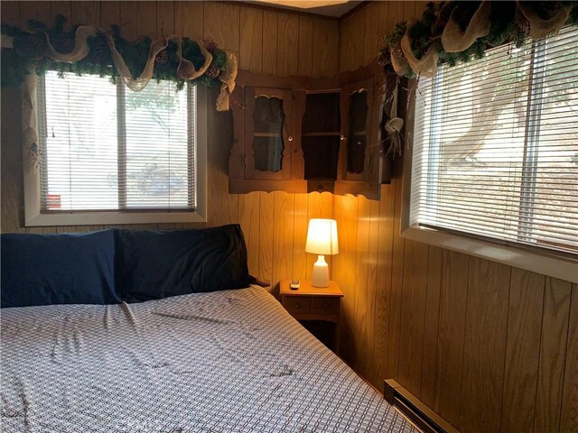 bedroom featuring baseboard heating and wooden walls