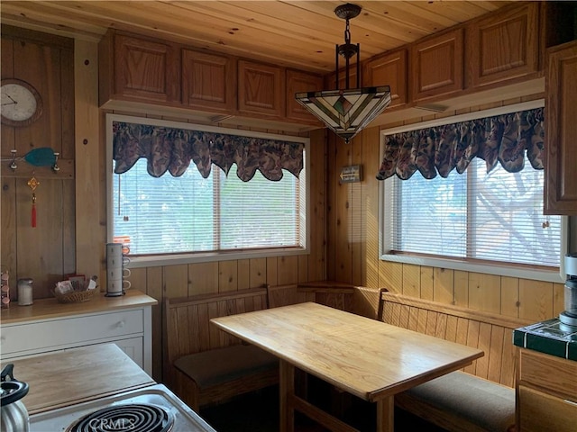 kitchen featuring wooden ceiling, hanging light fixtures, breakfast area, and wooden walls