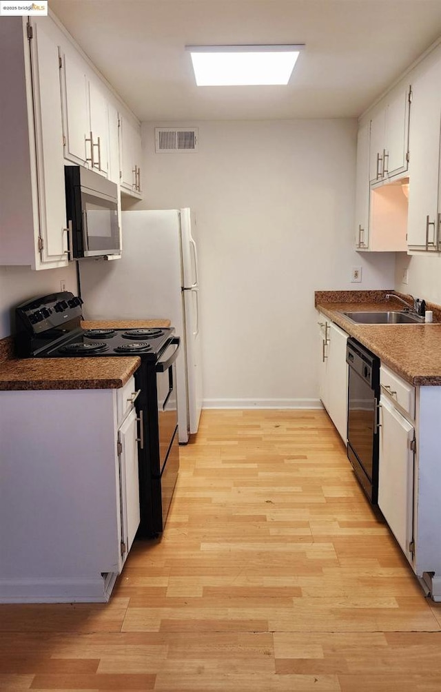 kitchen with sink, white cabinets, light wood-type flooring, and black appliances