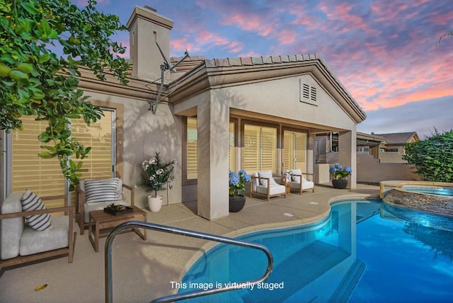 back house at dusk featuring a patio area and a swimming pool with hot tub