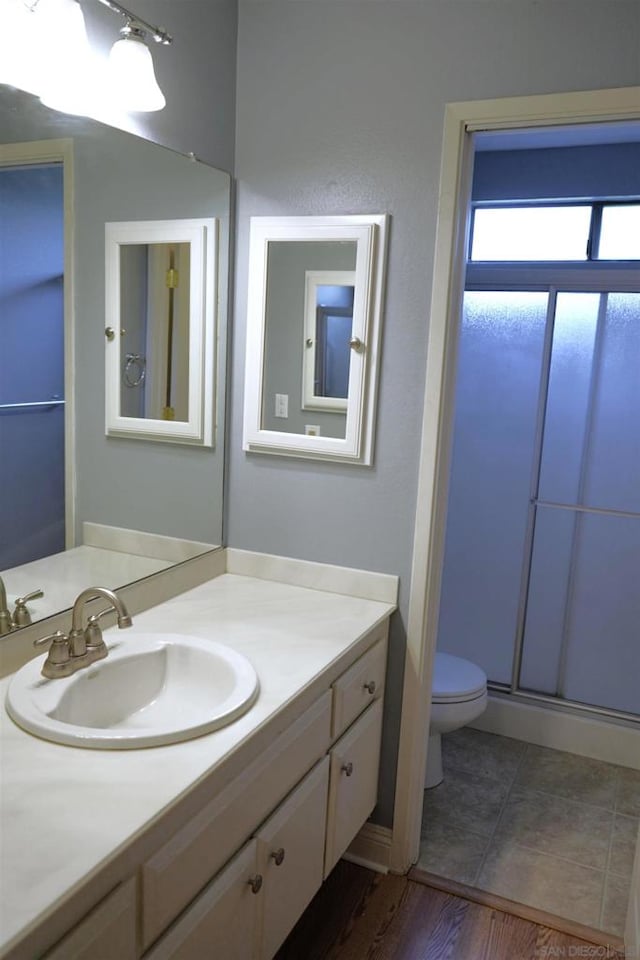 bathroom with toilet, vanity, an enclosed shower, and hardwood / wood-style floors