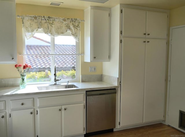 kitchen with sink, white cabinets, stainless steel dishwasher, and hardwood / wood-style floors