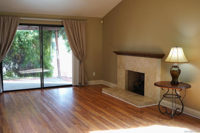 unfurnished living room with wood-type flooring, lofted ceiling, and a fireplace