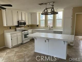 kitchen with sink, a kitchen island, white cabinetry, and white range with gas cooktop