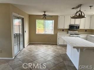 kitchen with ceiling fan, a breakfast bar, white cabinetry, and range