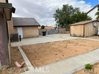 view of yard with central air condition unit, a storage shed, and a patio