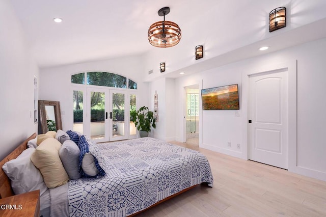 bedroom featuring vaulted ceiling, light hardwood / wood-style flooring, and french doors