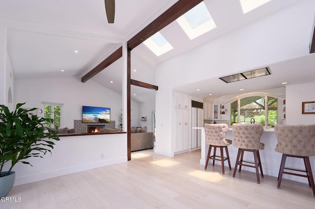 kitchen with light wood-type flooring, kitchen peninsula, lofted ceiling with skylight, and a breakfast bar