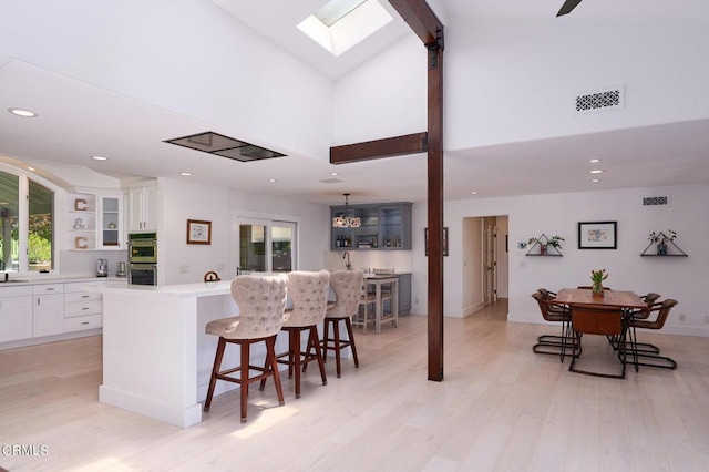 kitchen featuring white cabinets, a breakfast bar, stainless steel double oven, and a kitchen island