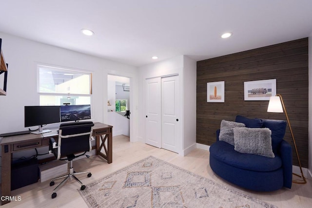 home office with wood walls and light hardwood / wood-style flooring