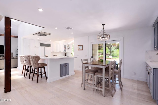 dining area with light wood-type flooring and a notable chandelier