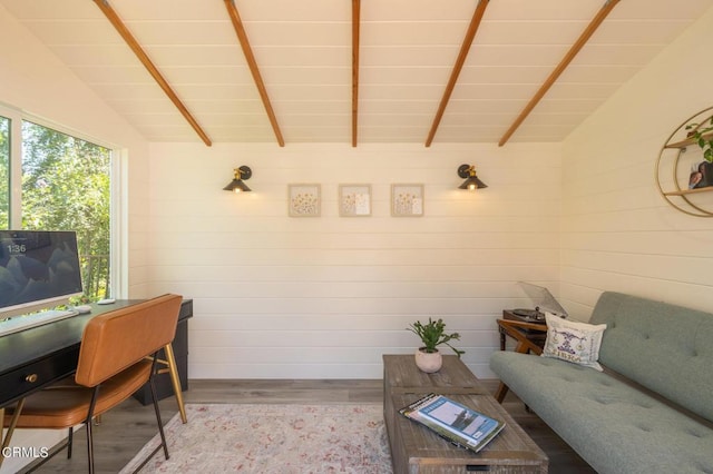 living room with wood walls, light hardwood / wood-style flooring, and vaulted ceiling with beams