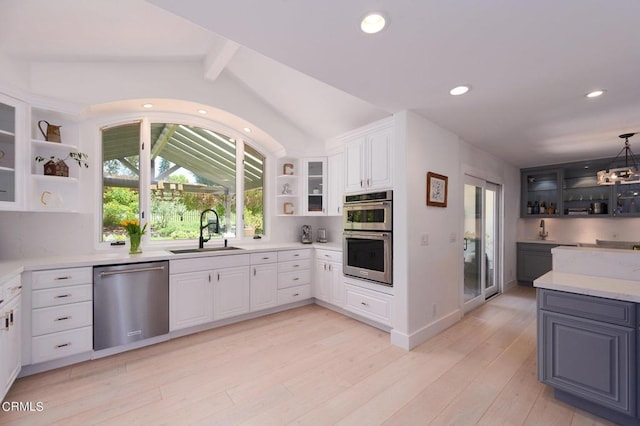 kitchen featuring appliances with stainless steel finishes, vaulted ceiling with beams, hanging light fixtures, white cabinets, and sink