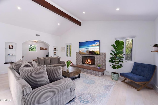 living room featuring light hardwood / wood-style floors, a wealth of natural light, and lofted ceiling with beams