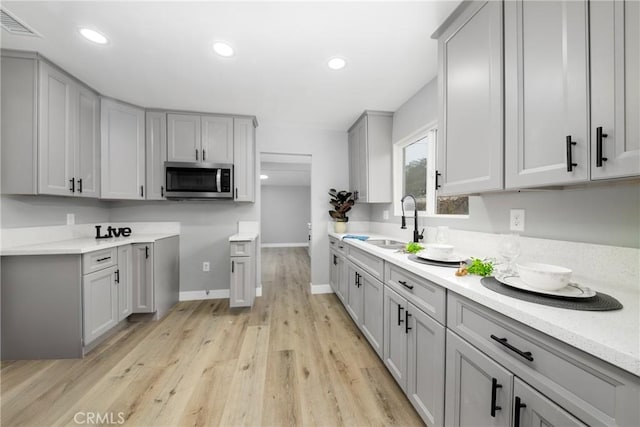 kitchen featuring light wood-type flooring, gray cabinetry, and sink