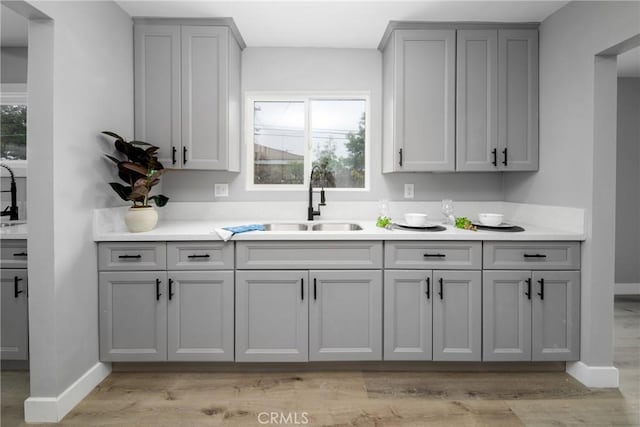 kitchen with light hardwood / wood-style floors, gray cabinets, and a healthy amount of sunlight