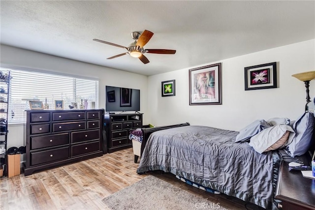 bedroom with ceiling fan, a textured ceiling, and light hardwood / wood-style floors