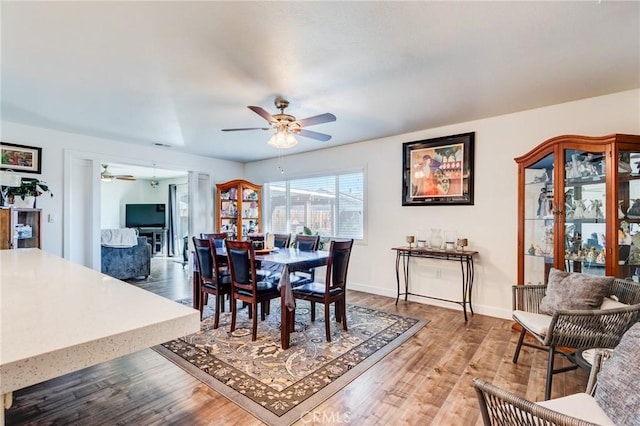 dining space with ceiling fan and wood-type flooring