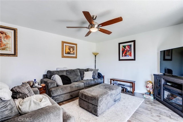 living room featuring light hardwood / wood-style floors, ceiling fan, and a fireplace