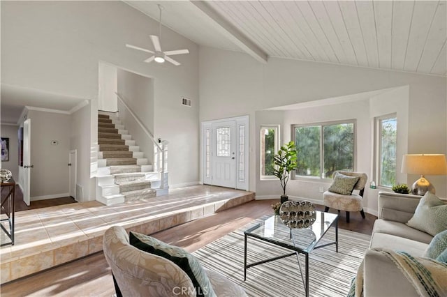 living room with visible vents, baseboards, stairway, lofted ceiling with beams, and light wood-style flooring