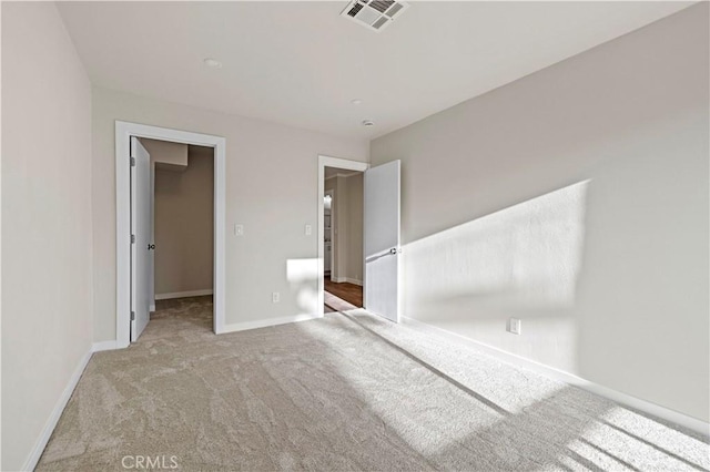 unfurnished bedroom featuring a spacious closet, light colored carpet, and a closet