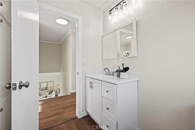 bathroom featuring vanity, crown molding, wood finished floors, and a textured wall